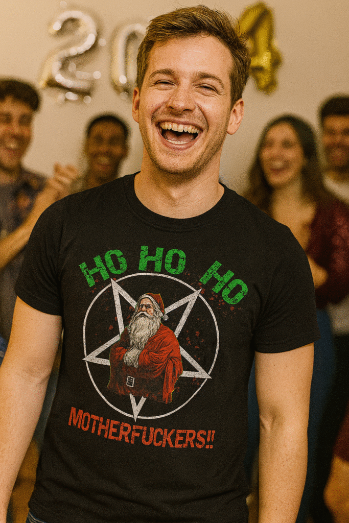 Chico riendo en una fiesta de Nochevieja con amigos, vistiendo camiseta con Papá Noel satánico y texto HO HO HO mutherfuckers, parte de la colección de camisetas góticas y alternativas